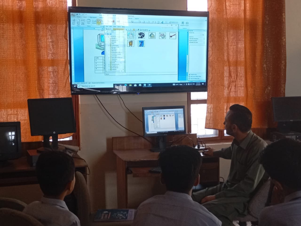 Teacher giving a computer lab lesson to students