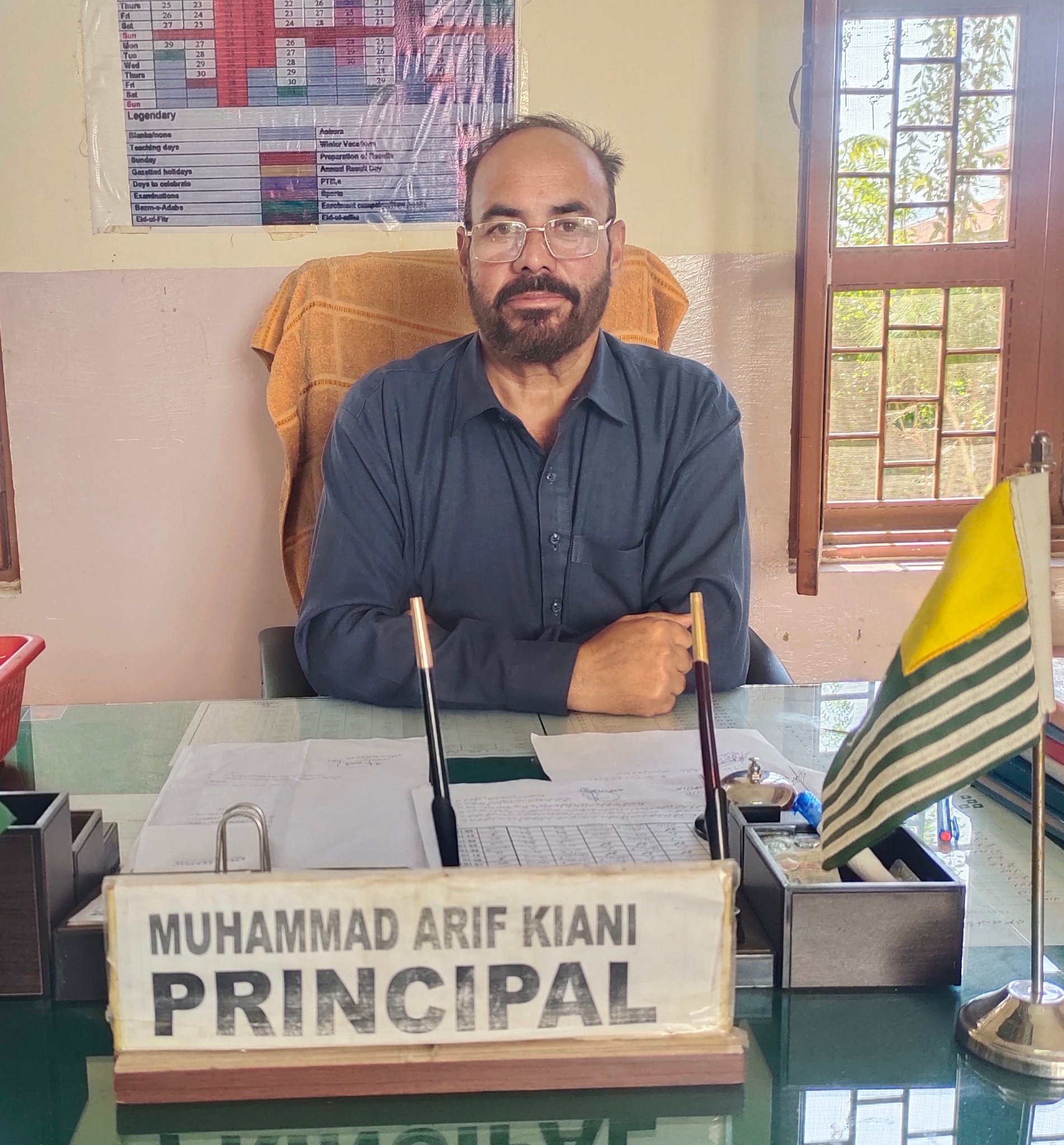 Muhammad Arif Kiani, Principal of Government Boys High School Ranjata, seated at his office desk