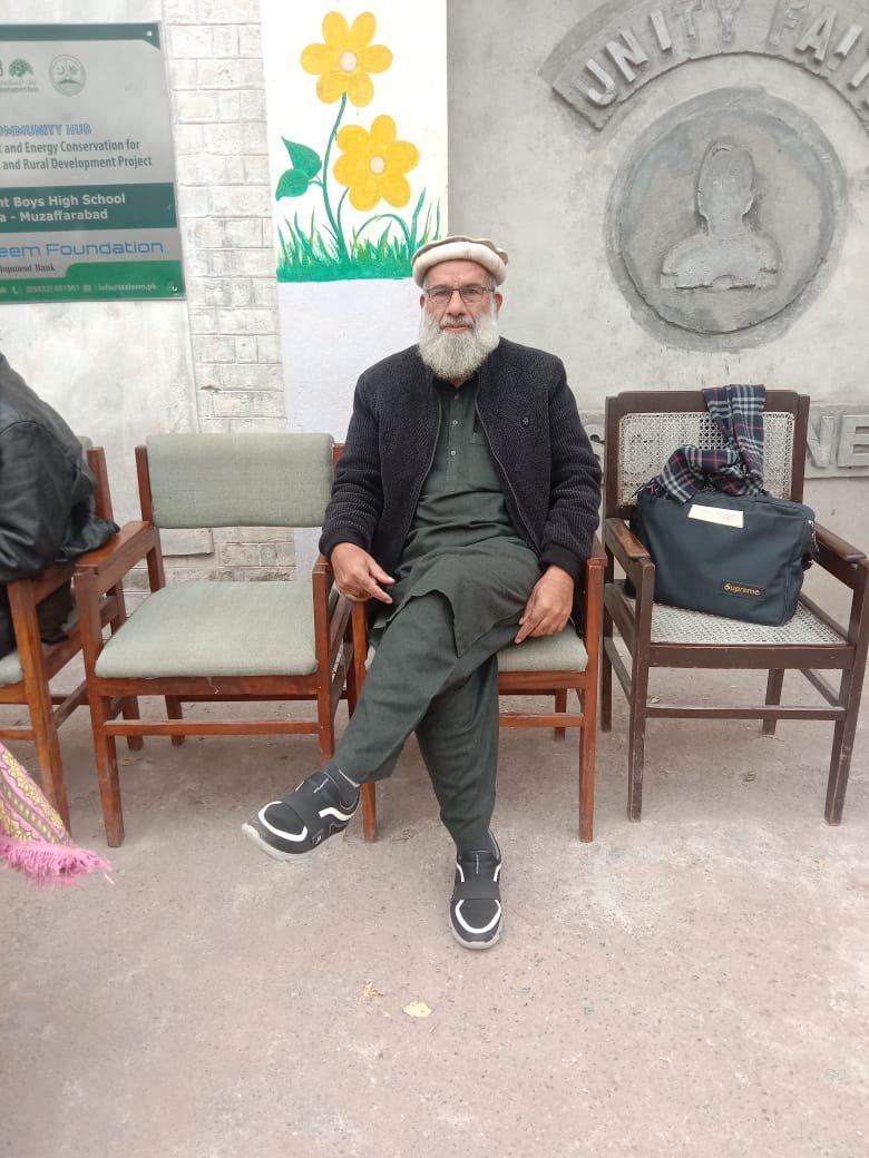 Staff member seated in front of the school sign